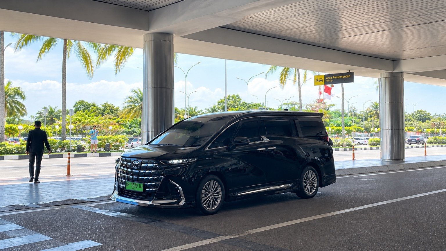 Black Toyota Alphard at a covered pickup area in Batam.